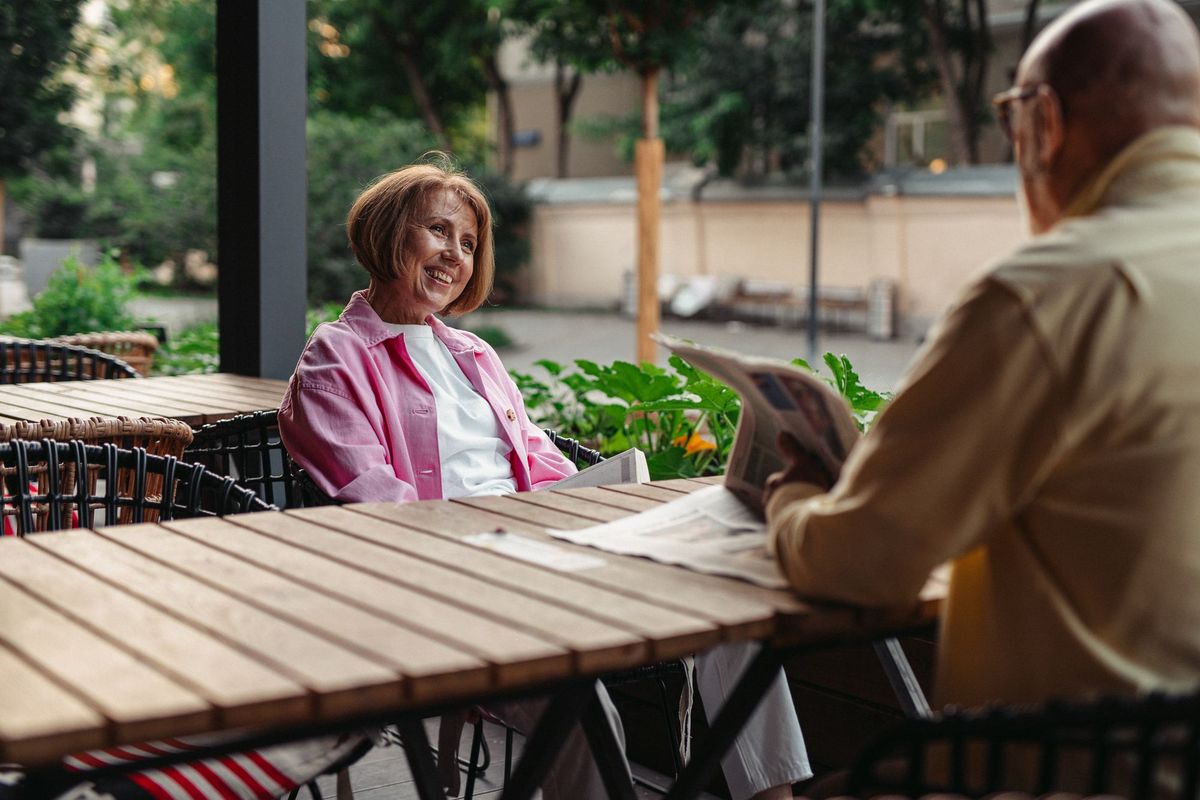 An older couple talking at an outdoor café table
