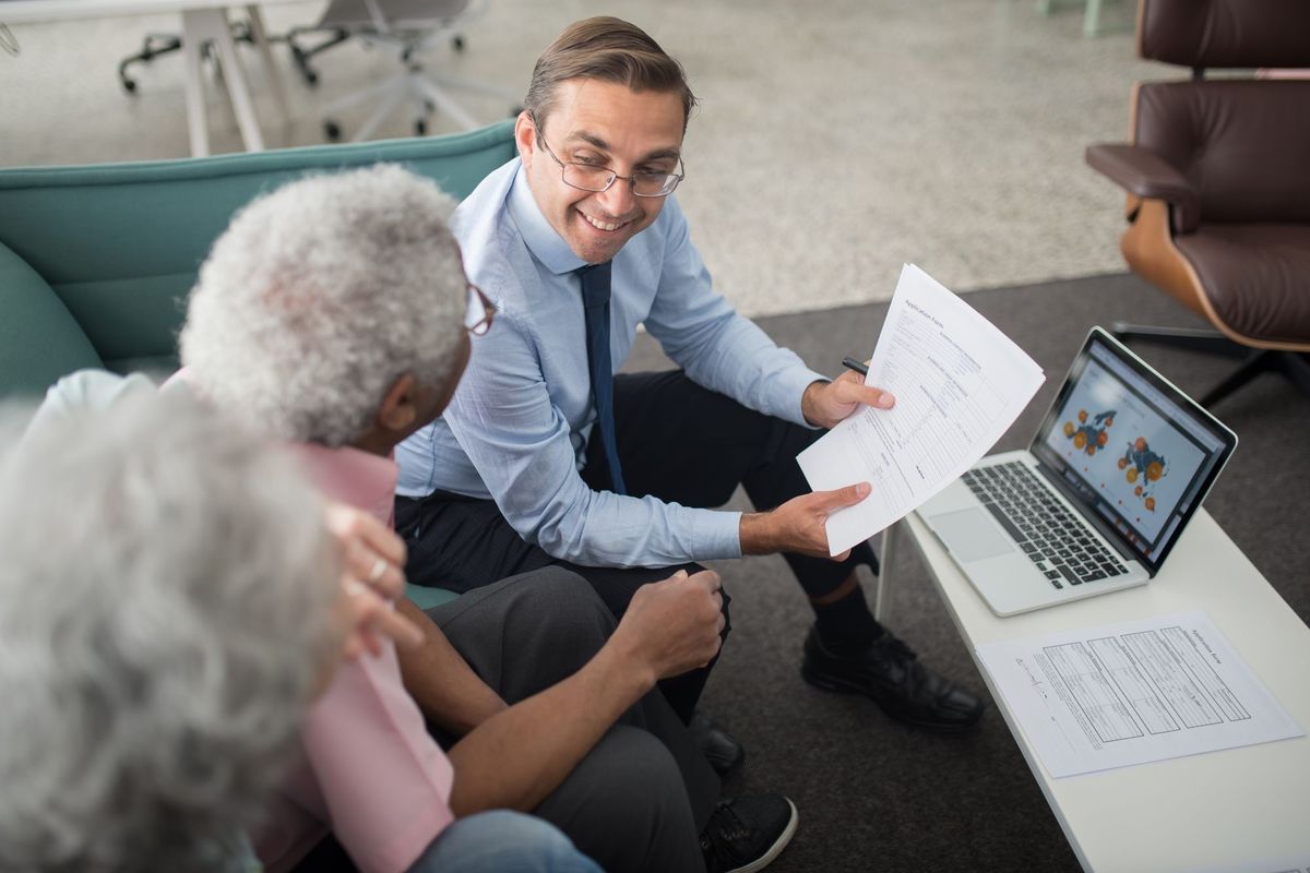 An advisor going over paperwork with an older couple at home