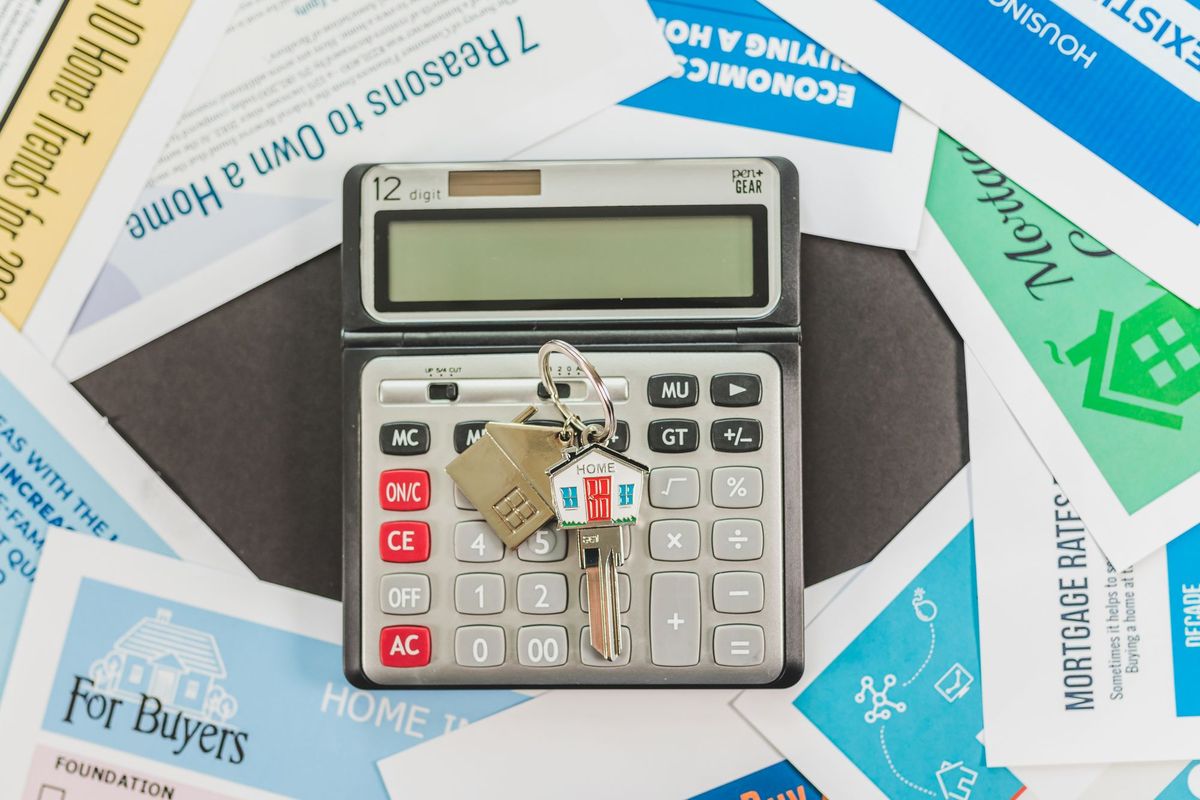 A calculator and house keys on home-buying brochures
