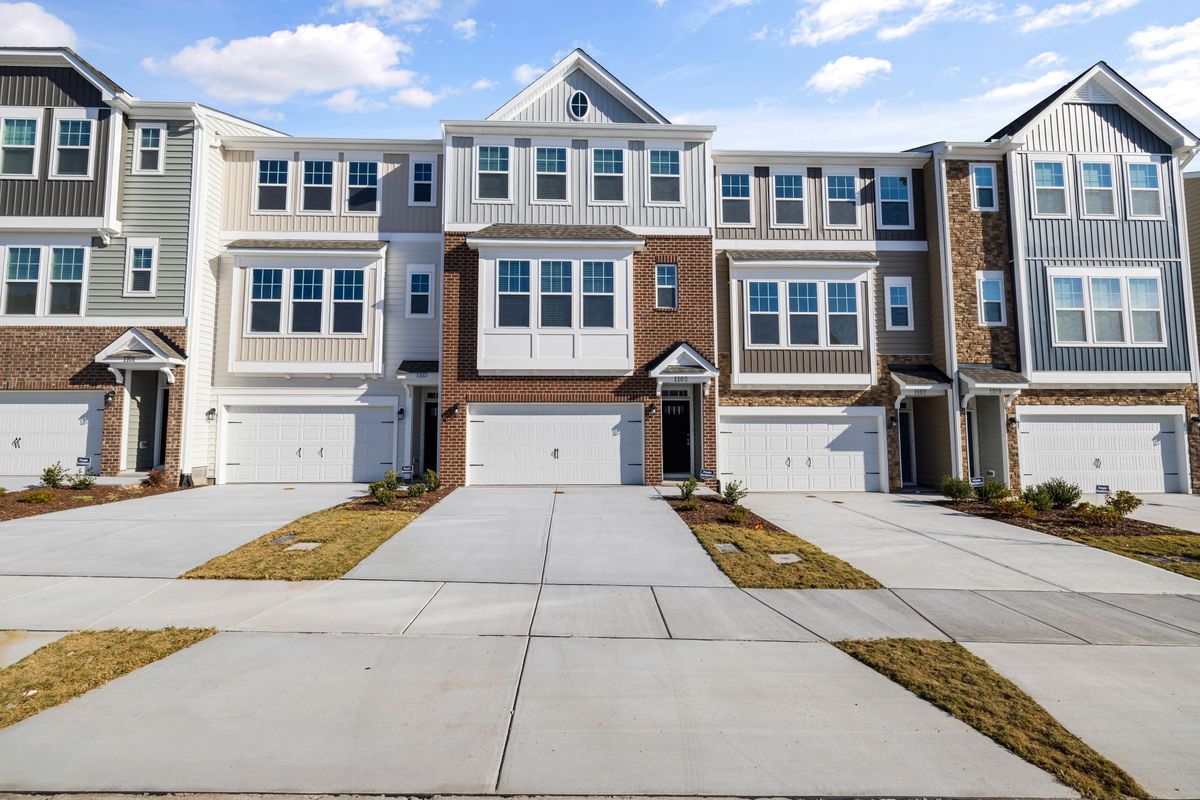 A row of two-story townhomes with garages and driveways