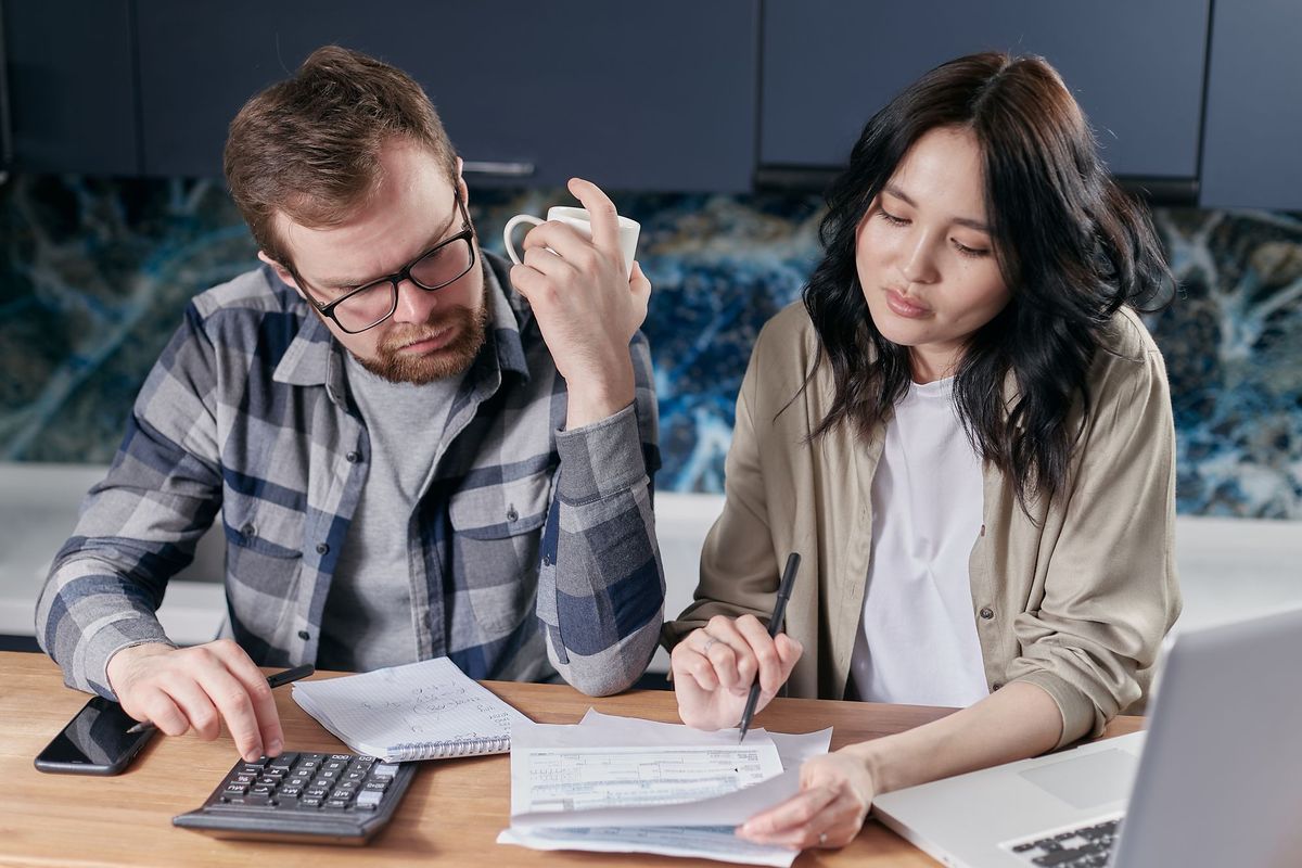 A couple going over their budget with a calculator and a laptop