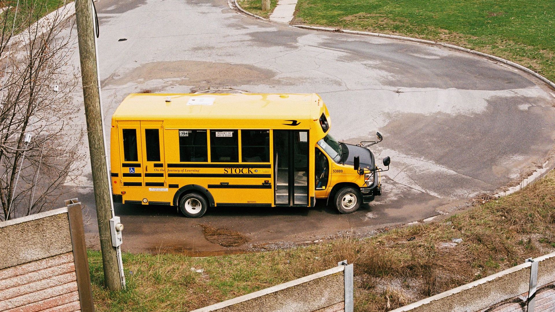 A yellow school bus at a neighborhood roundabout
